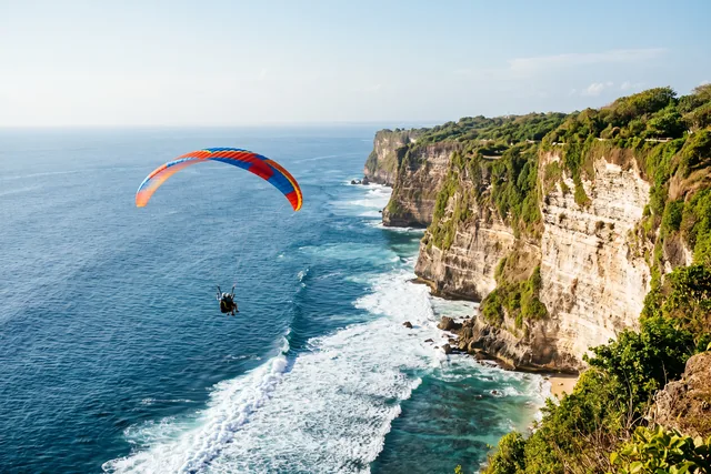 Tandemový paraglajdista nad útesmi a oceánom na juhu Bali