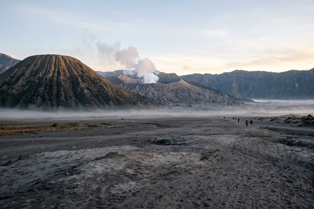 The Bromo caldera at sunrise: the ribbed cone of Mount Batok, Bromo's smoking crater behind it and the misty Sea of Sand