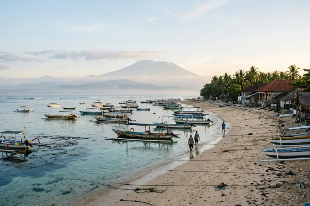 Rybárske lode v plytkej zátoke pri pláži Jungutbatu na Nusa Lembongan, v diaľke sopka Agung